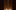 Two cream candles are lit in the darkness