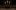 Three lit candles in the dark shadows of an indoor wooden theatre.