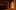 A row of books sits on the wooden gallery of the Sam Wanamaker Playhouse, cast in candlelight and shadows.