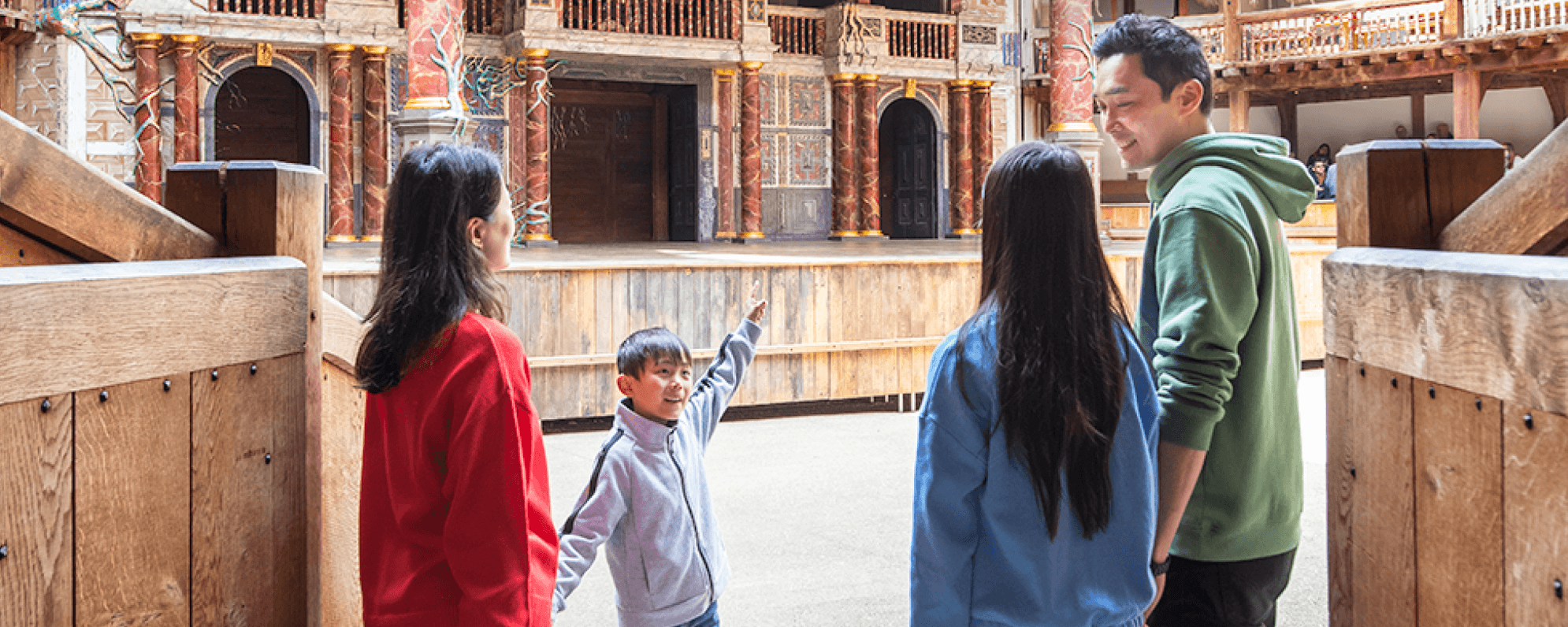 A family stand in the Globe Theatre. The little boy is pointing excitedly at the stage.