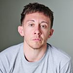 Charlie Josephine wearing a grey t-shirt and looking directly at the camera.