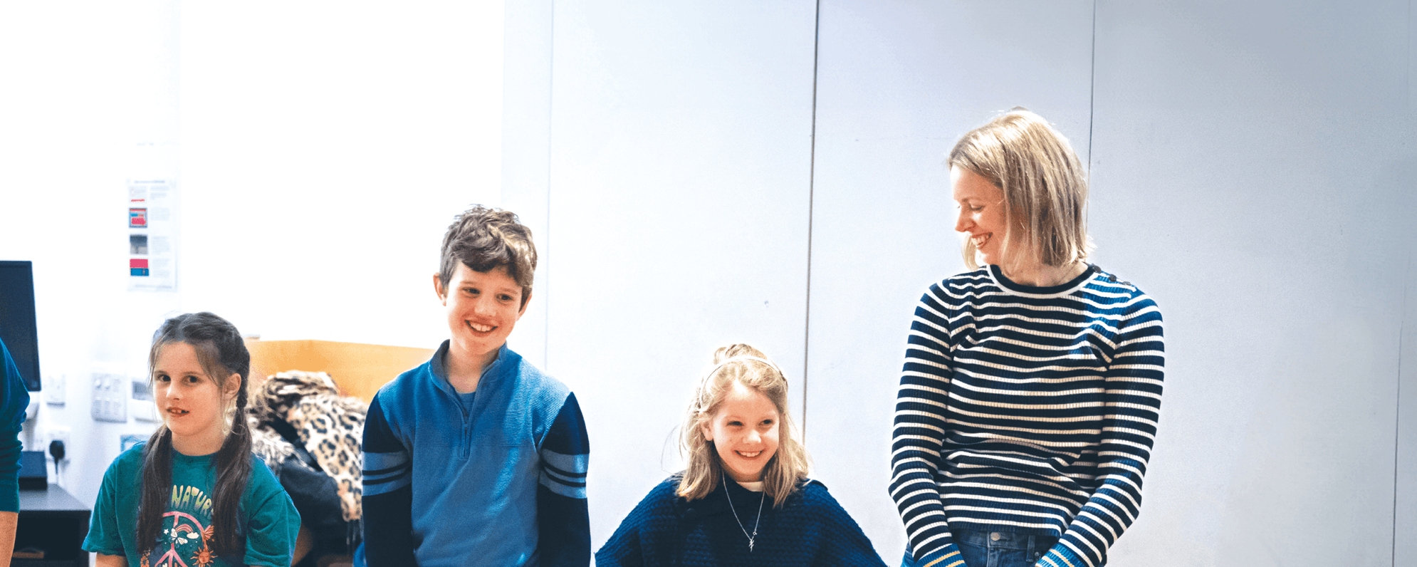Three children and an adult stand in a workshop.