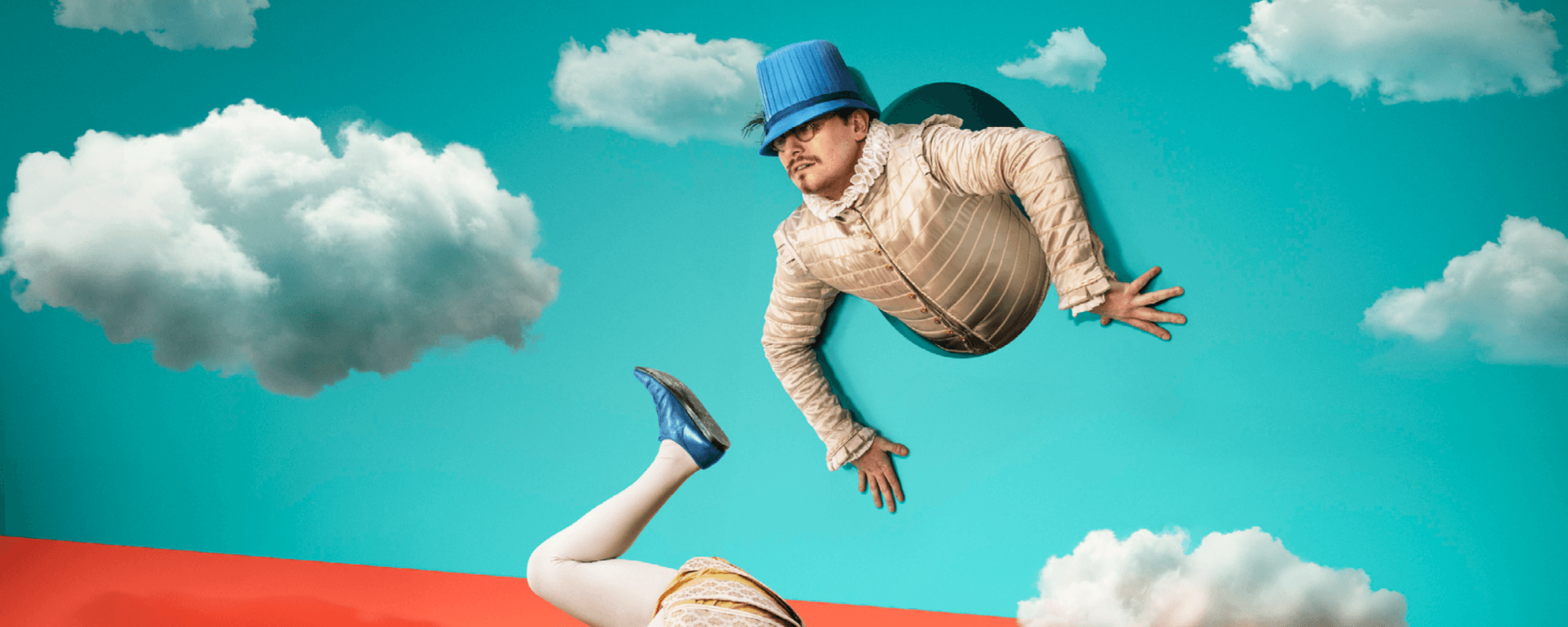 The torso of a man in Elizabethan dress appears from a hole in a blue backdrop with clouds. His legs appear from a different hole in the ground