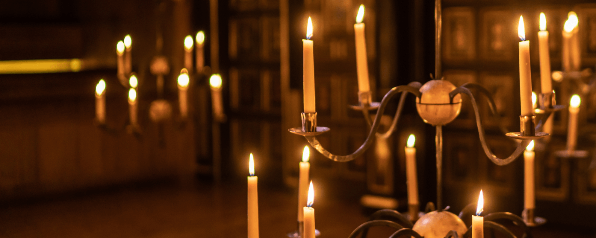 3 candelabras hang down from the ceiling in an old Elizabethan style theatre