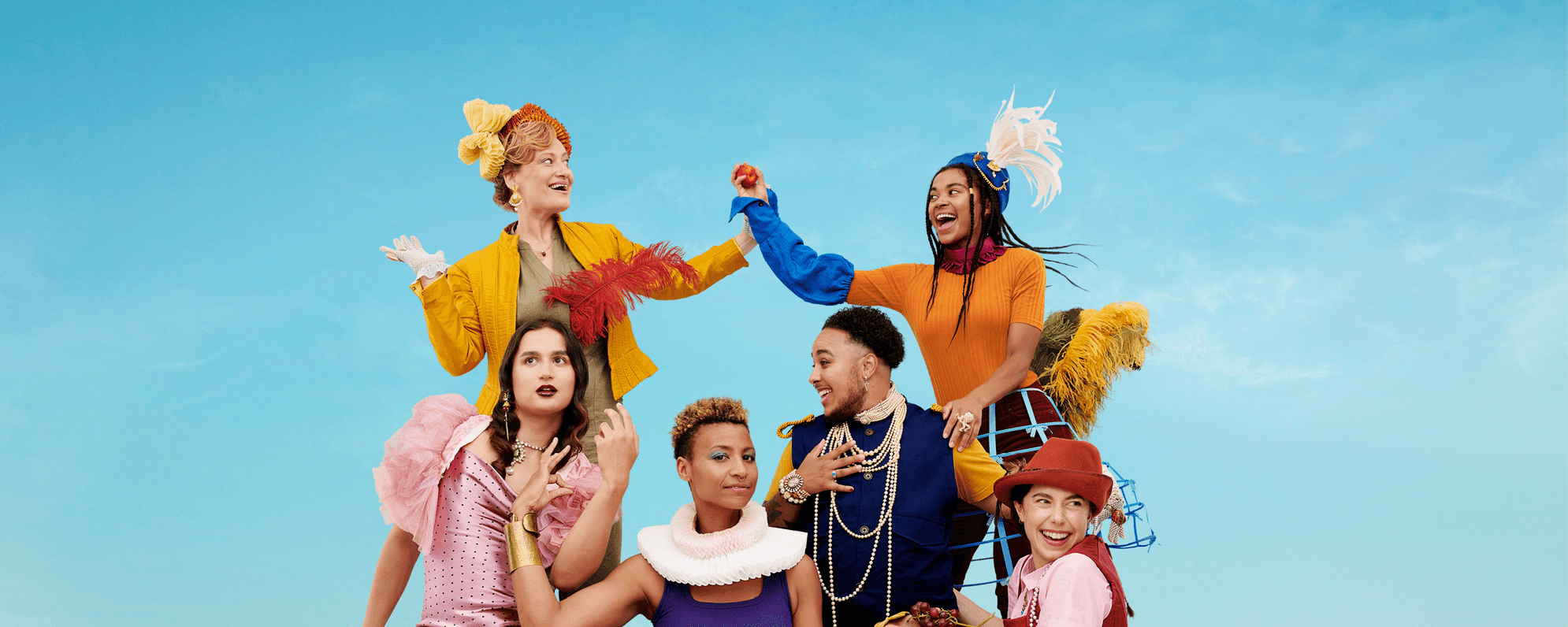 A group of six actors are wearing colourful clothes with Elizabethan accessories.