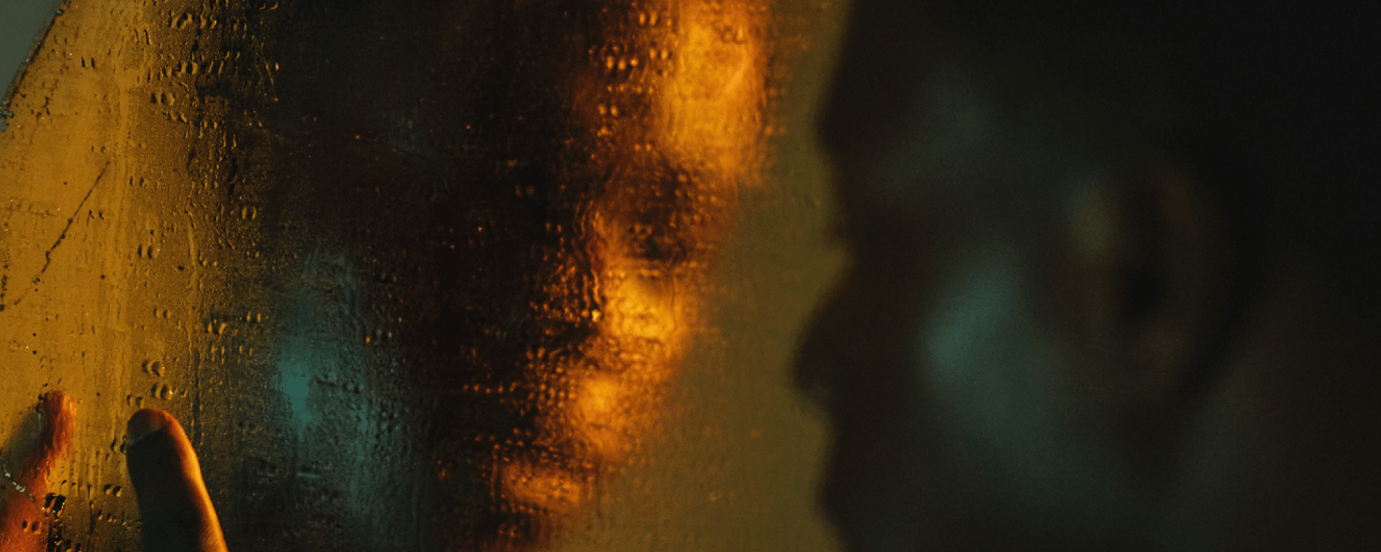 An actor looking into a mirror. The mirror is covered in water which distorts the reflection.