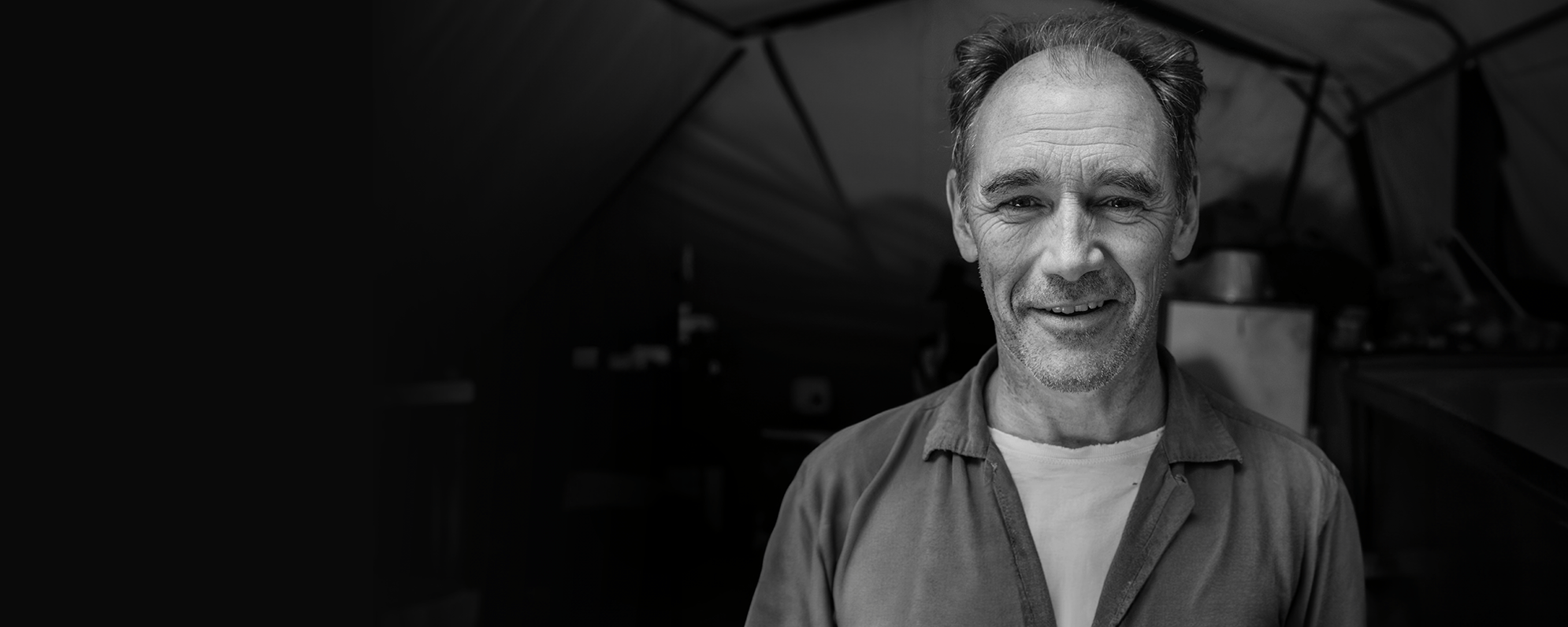 A black and white photo of an actor smiling into camera