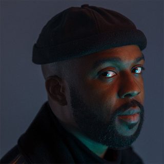 Headshot of Ken Nwosu wearing a black cap and looking at the camera.