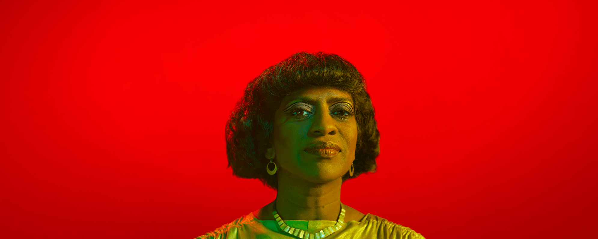 Nadia Nadarajah as Cleopatra against a bright red background.