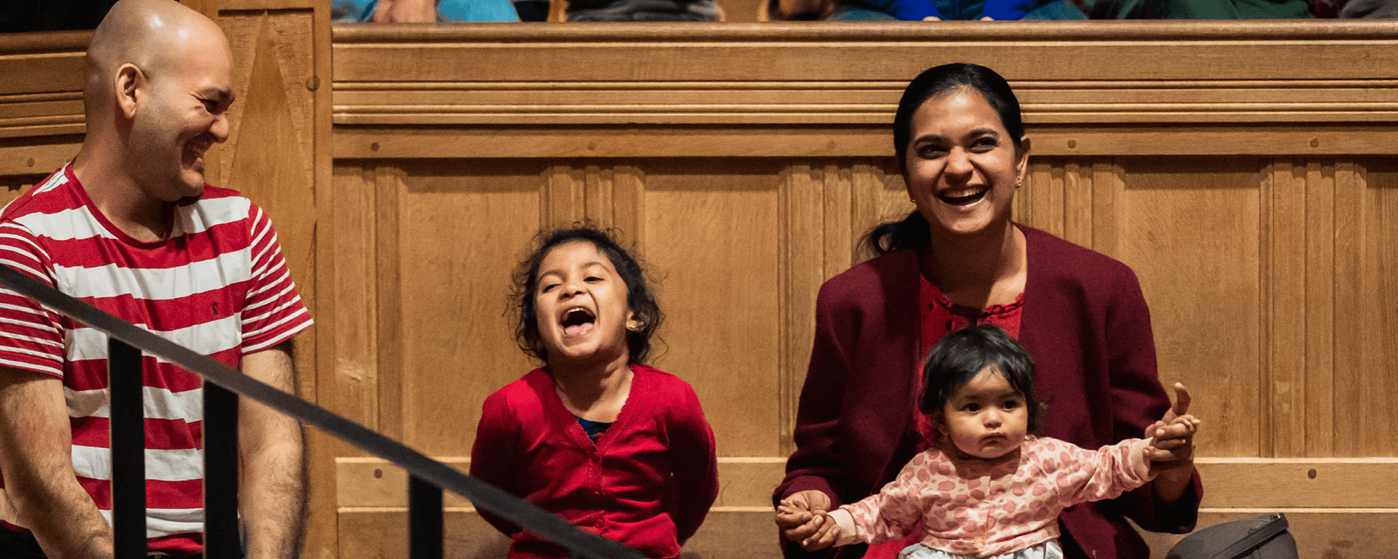 A family sat in the Sam Wanamaker Playhouse laughing at the stage.