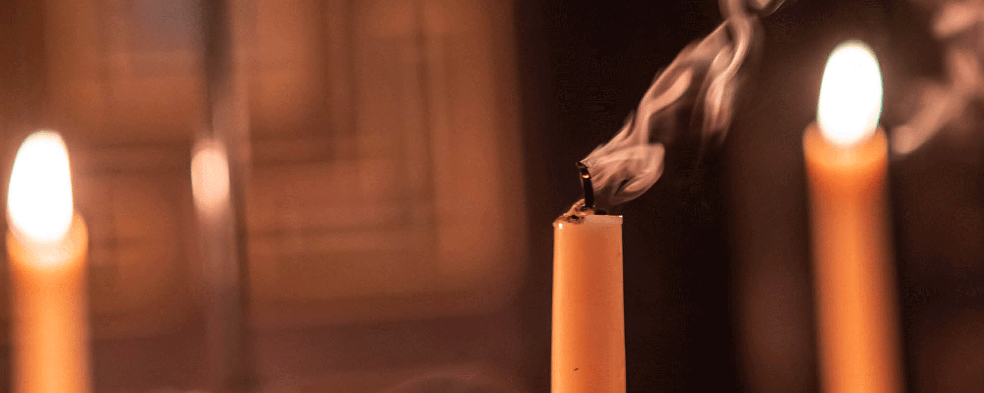Three candles, two lit and one recently extinguished.