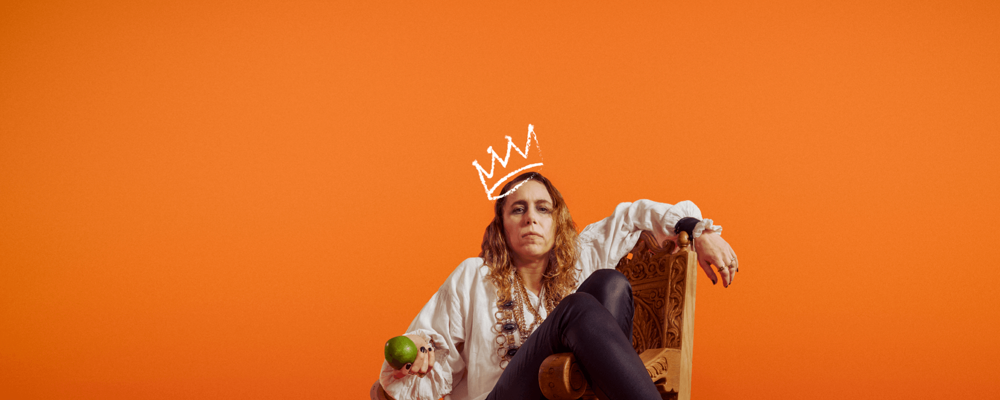 Michelle Terry sat on a thrown holding an apple depicting Richard III in front of an orange background with a white graphic crown drawn above her head.