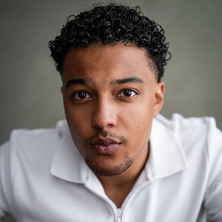 Headshot of Joshua John, wearing a white polo shirt and looking directly at the camera.