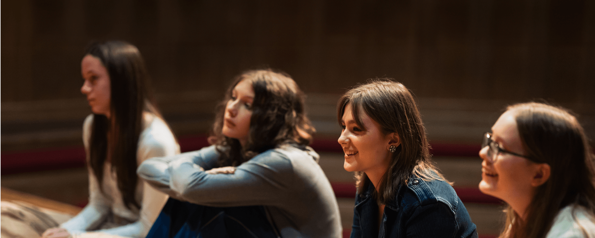 Four young females sat on the Globe stage in a workshop.