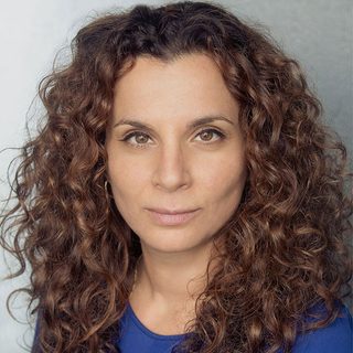 Headshot of Suzanne Ahmet looking directly at the camera and wearing a blue top.