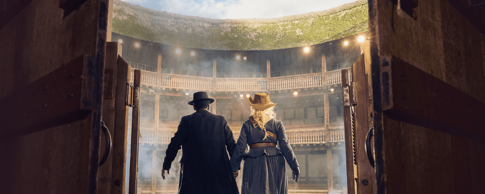 Actors playing Romeo & Juliet at the Globe - they are dressed like characters in a Western, with long coats and Stetsons