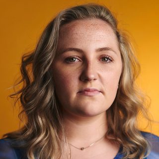 Molly Madigan looking directly at the camera in front of a yellow background.