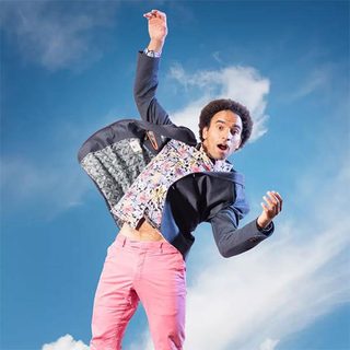 Joseph Coelho jumping in the air with a blue sky in the background.
