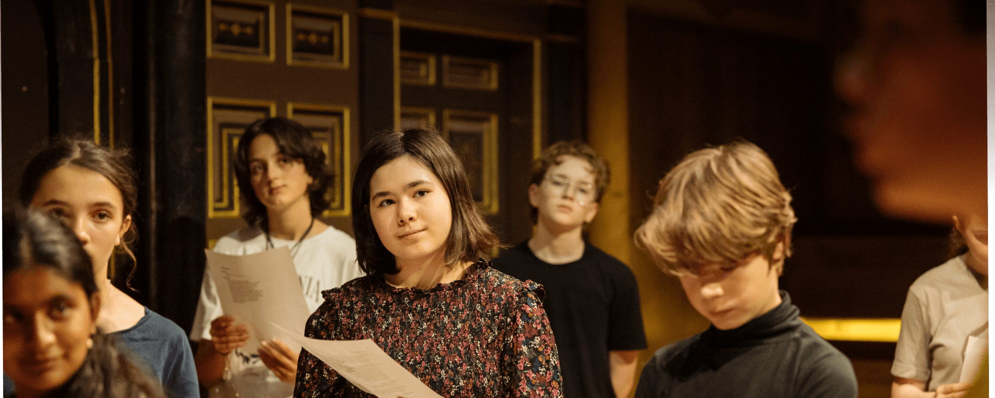 A group of children stand on the Sam Wanamaker playhouse stage, during a workshop for young people.