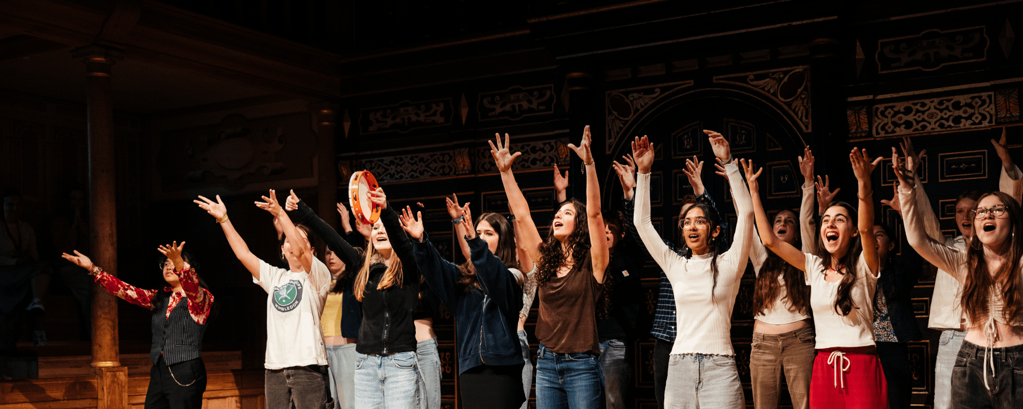 Group of cheering young people on stage with their hands raised