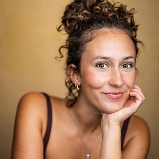 Headshot of Sarita Gabony, looking directly at the camera and resting their head in their palm.