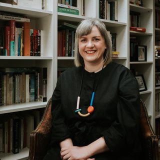 Amber Massie-Blomfield, smiling at the camera, in a library
