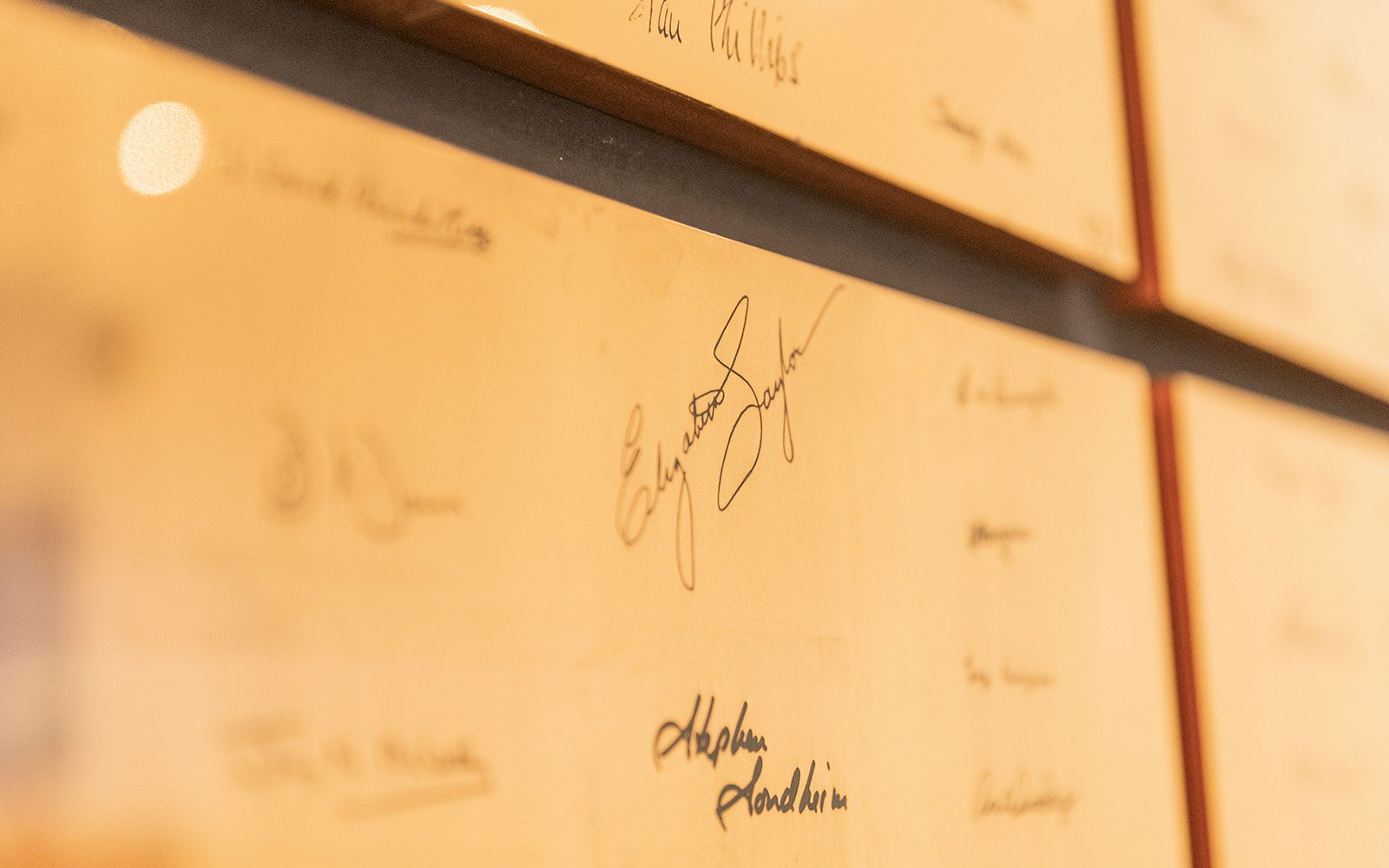 A bronze square with engraved signatures on it. The camera is focused on the signatures of Elizabeth Taylor and Stephen Sondheim.