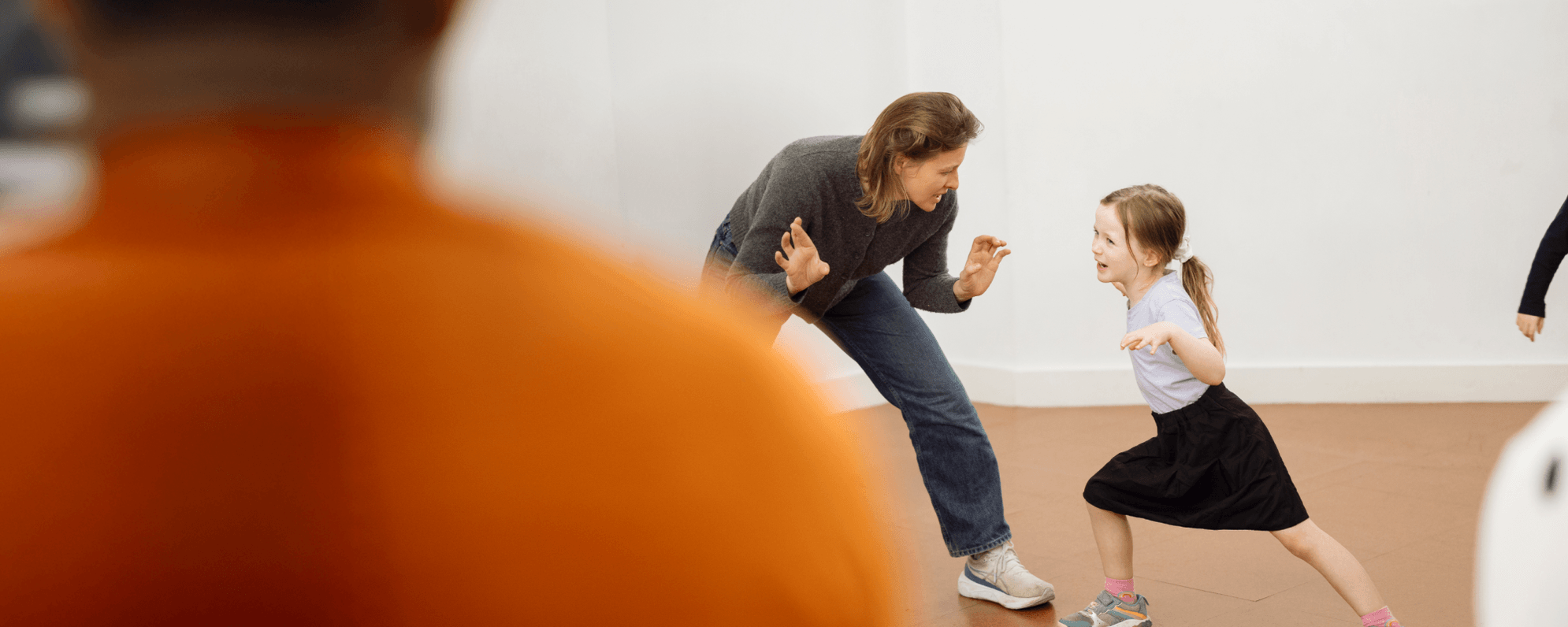 A parent crouched down and facing a child as they take part in a workshop.