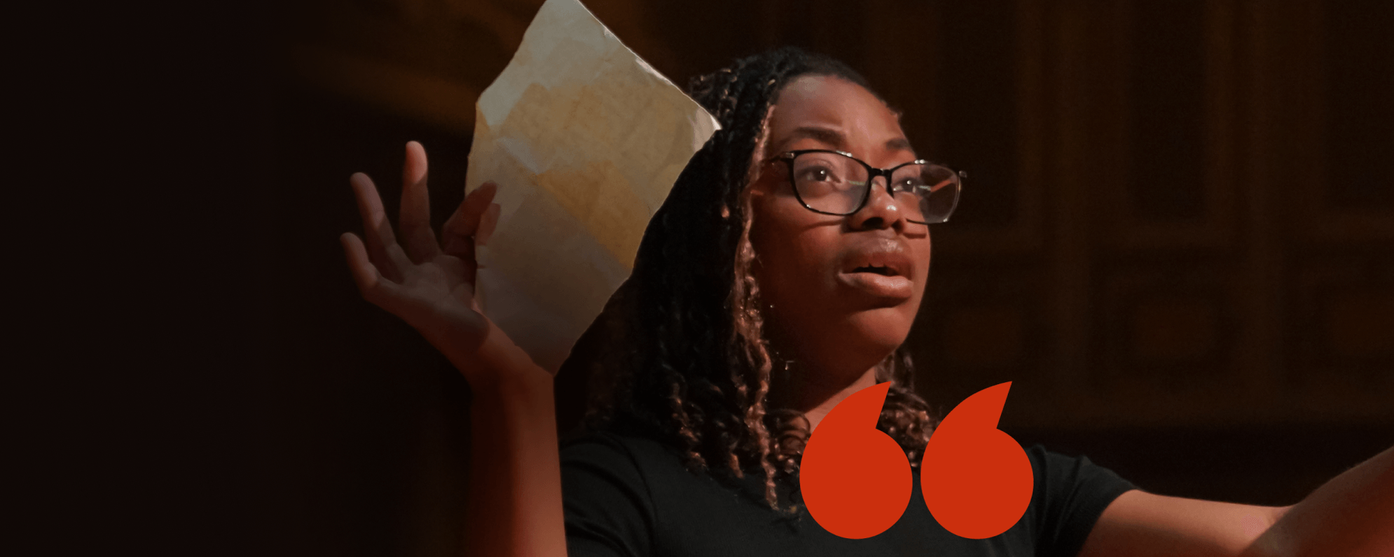 A young person holds up their arms, a piece of paper in one hand.