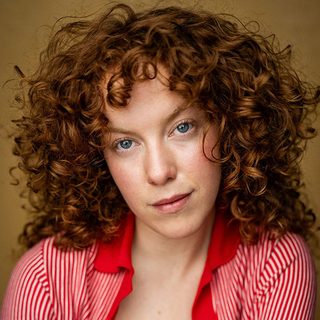 Headshot of Zannie Belfield wearing a red shirt and looking directly at the camera.