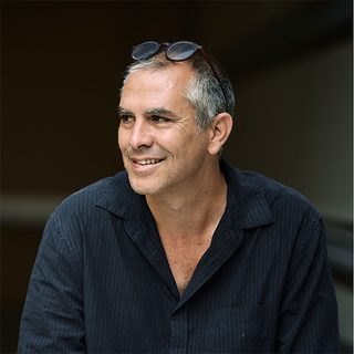 Headshot of Amir Nizar Zuabi smiling and looking to one side.