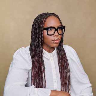 Faridah Àbíké-Íyímídé wearing a white shirt and looking away from the camera.