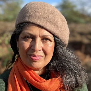Sita Brahmachari wearing a woollen beret and an orange scarf.