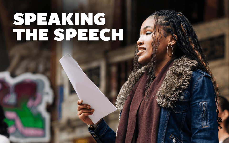 Speaking the Speech. A person holding a piece of paper, smiling.
